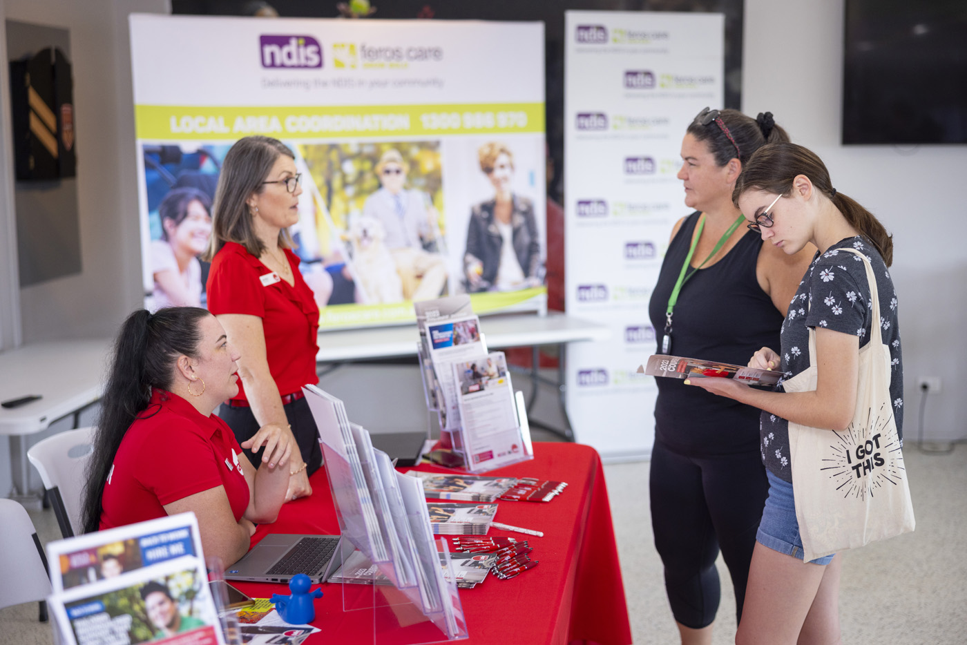 Mother and daughter talking to team members of TAFE Queensland stand at the All Abilities Employment Expo