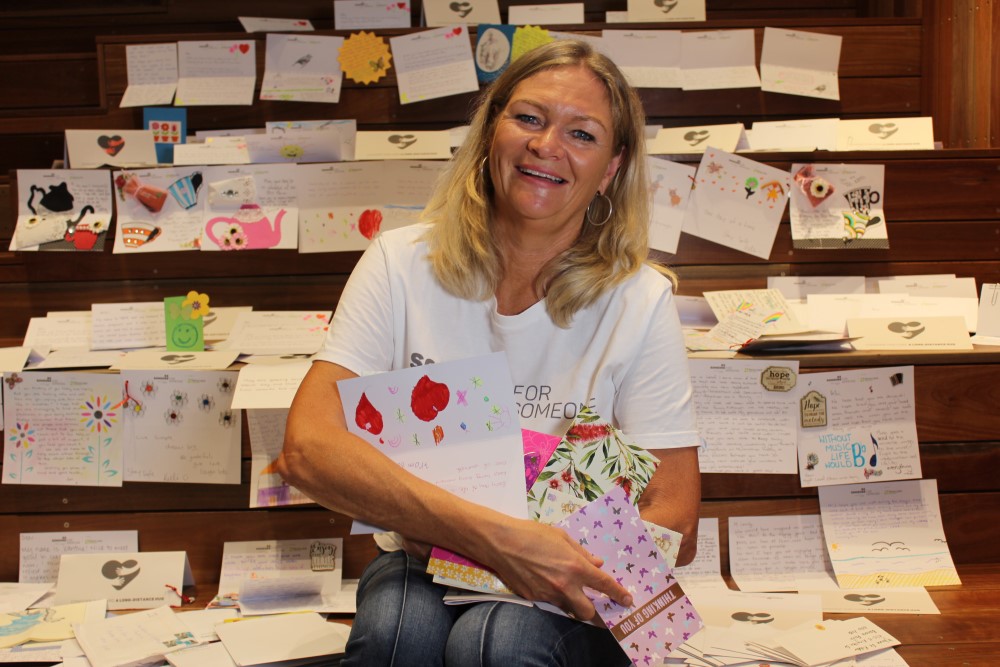 Woman sitting on wooden stairs surrounded by handwritten letters and cards