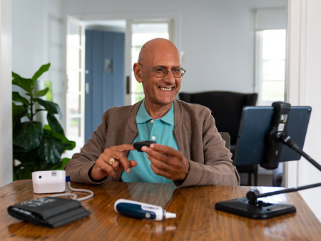 Man using heart rate monitor while talking to nurse over video call