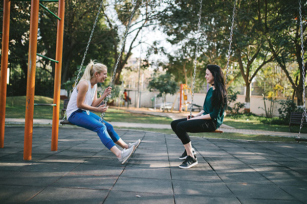 two people sitting on swings