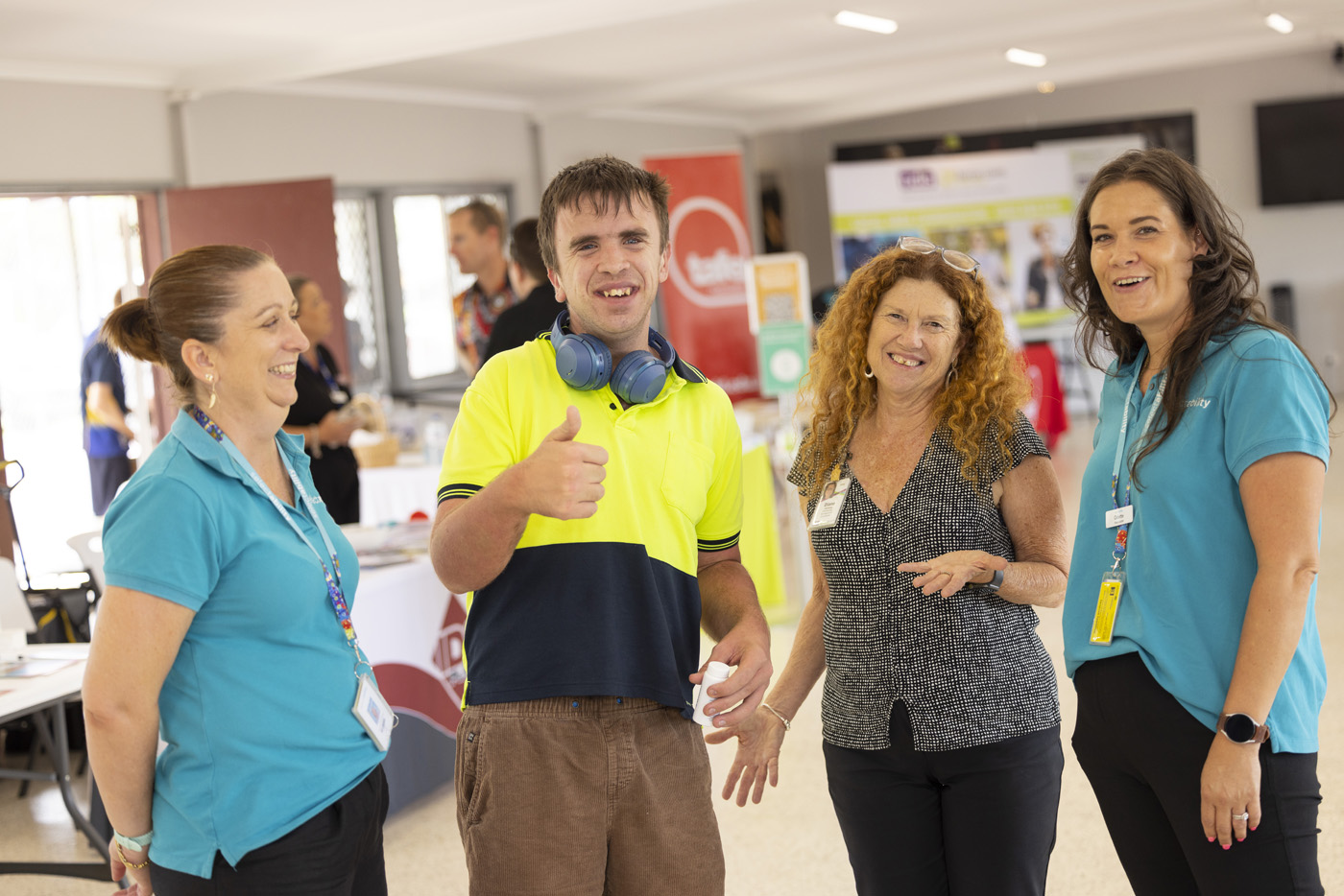 People looking to camera smiling. One man in a yellow high-vis top showing a thumbs up.